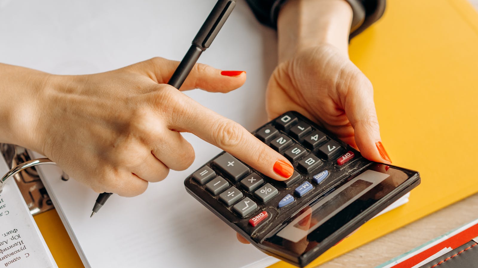 Mains d'une femme utilisant une calculatrice pour faire des comptes
