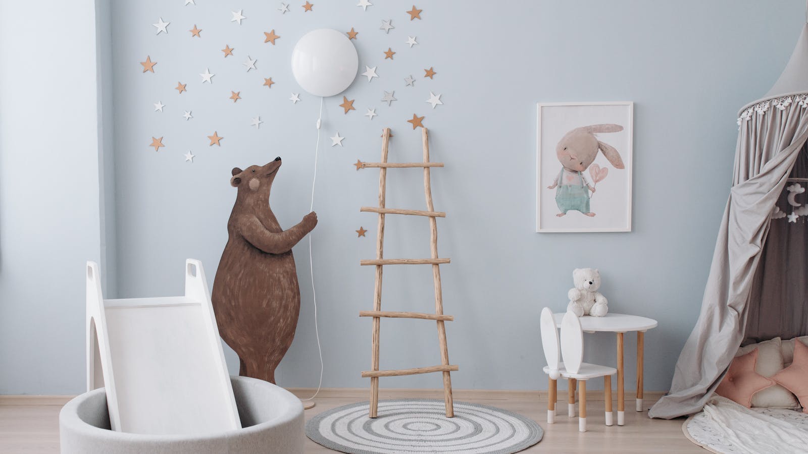 Chambre d'enfant décorée avec des étoiles murales, un stickers ours et un lit à baldaquin